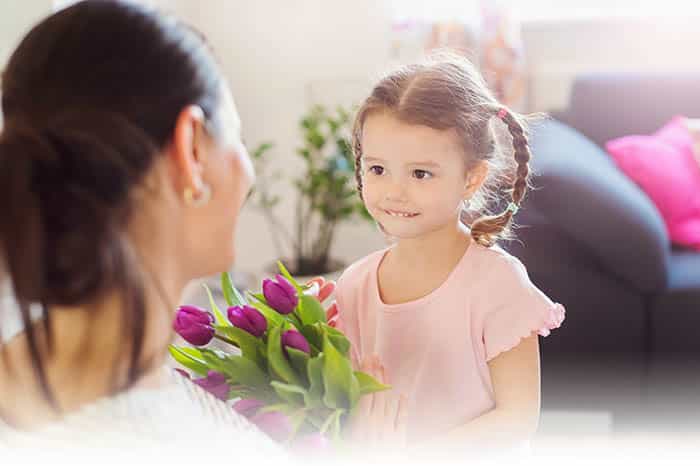 Mothers day, little girl giving flowers to her mum